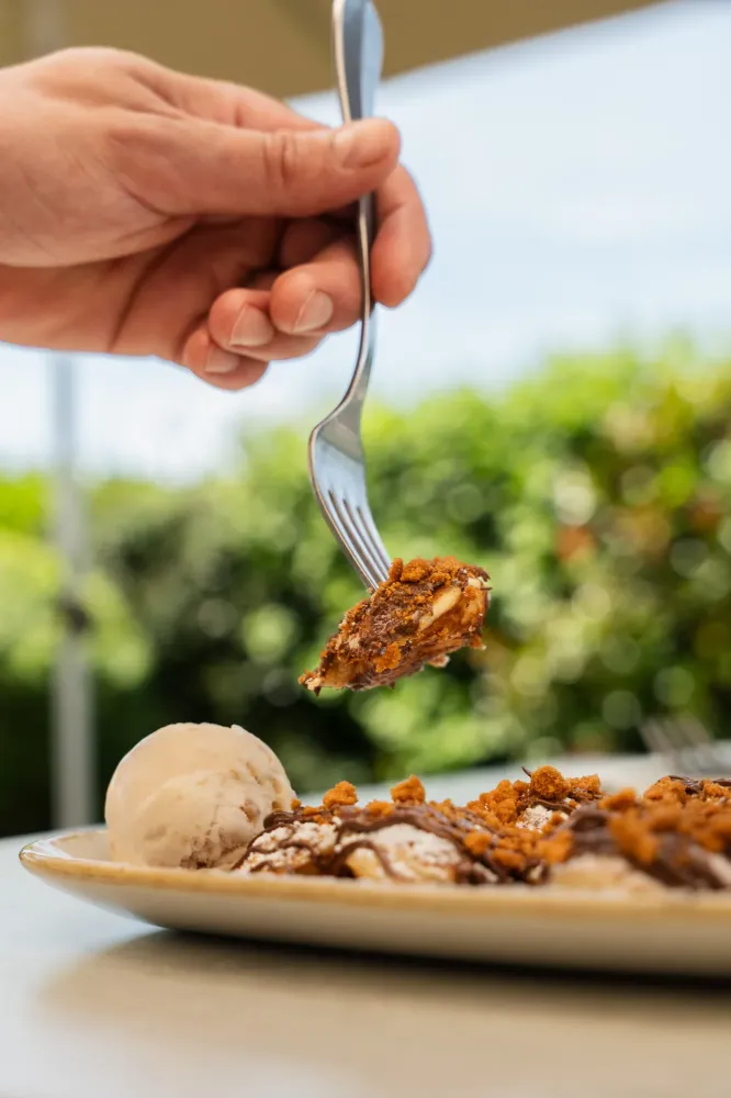 Main tenant une fourchette au dessus d'une assiette de dessert