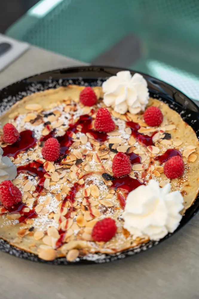 Un dessert sur une assiette, garni de framboises et d'amandes